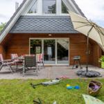 Haus mit Terrasse, Sitzgelegenheiten und Grillplatz im Garten.