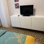 Schlafzimmer mit Bett, Fernseher und Wandbildern.