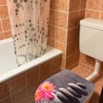 Badezimmer mit Badewanne, Toilette und Duschvorhang mit Punktmuster.
