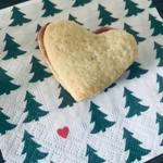 Herzformiger Keks mit Füllung auf Tischserviette mit Tannenbaum-Muster