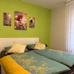 Schlafzimmer mit Bett, grüner Wand und drei Wandbildern mit roten Mohnblumen.