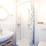 Badezimmer mit Dusche, Waschbecken und Toilette. Duschvorhang mit buntem Muster.