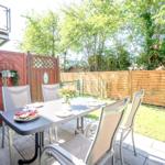 Terrasse mit Tisch, Stühlen, Grill und Blumenarrangement.