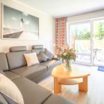 Wohnzimmer mit Sofa, Tisch und Blick auf die Terrasse.