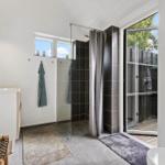Badezimmer mit Dusche, Waschbecken und Blick auf den Garten.