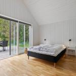 Schlafzimmer mit Balkon, weißer Wandverkleidung und Holzboden.