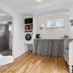 Wohnraum mit Waschmaschine, Fenster und Bett. Badezimmer im Hintergrund.