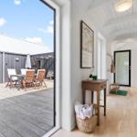 Hausgang mit Holzboden und Blick auf Terrasse mit Gartenmöbeln.