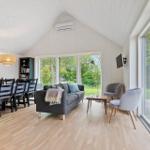 Wohn- und Essbereich mit Sofa, Tisch, Stühlen und großem Fenster. Holzboden und weiße Wände.