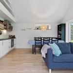 Küche, Essbereich und Wohnbereich mit blauem Sofa und Holzboden.