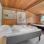 Schlafzimmer mit Doppelbett, Holzwand und Fenster. Zwei Wandbilder und Nachttische.