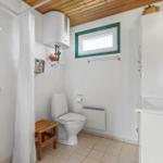 Badezimmer mit Dusche, Toilette und Waschbecken. Holzdecke und grünes Fenster.