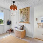 Eingangsbereich mit Wandbild, Sitzkissen und Blick ins Wohnzimmer.