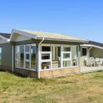 Moderne Strandvilla mit großem Fensterbereich und Terrasse. Blick auf das Meer.
