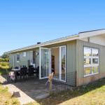 Ein Haus mit Terrasse und Gartentisch. Glasfront öffnet sich zum Innenraum.