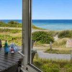 Terrasse mit Tisch und Stühlen bietet Blick auf Meer und Strand.
