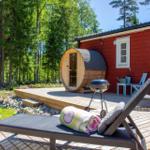 Roter Holzaufbau mit Sauna, Grill und Liege auf Terrasse im Wald.