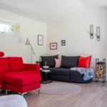 Ein Wohnzimmer mit rotem Sofa, schwarzem Sofa und Kaminofen.