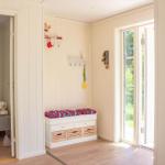 Eingangsbereich mit Sitzbank, Haken und Tür zum Schlafzimmer.