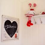 Wand mit Herz-Plakat und Stoffmaus auf Regal mit Haken.