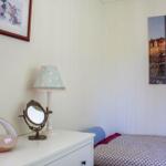 Schlafzimmer mit Bett, Nachttisch, Lampe und Wandbildern.
