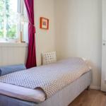 Ein Schlafzimmer mit Bett, Fenster und Tür. An der Wand hängt ein Bild.