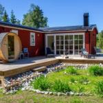 Rotes Holzhaus mit Terrasse, Sauna und Grillplatz im Grünen.