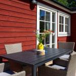 Roter Holzaufbau mit Terrasse, Tisch und Stühlen sowie Blumen in einem Topf.