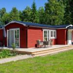 Rotes Holzhaus mit Terrasse, Garten und Wald im Hintergrund.