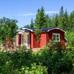 Rotes Holzhaus mit weißen Fenstern und Terrasse im Wald.