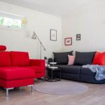 Ein Wohnzimmer mit rotem Sofa, schwarzem Sofa und Holzboden.