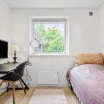Ein Zimmer mit Bett, Schreibtisch, Fernseher und Fenster mit Blick auf Bäume.