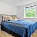 Schlafzimmer mit Bett, Nachttisch und Fenster zum Grün.