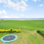 Grünes Feld mit Trampolin und Blick auf das Meer.