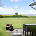 Außenbereich mit Grill, Tisch und Blick auf Meer und Grasfläche.