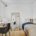 Schlafzimmer mit Bett, Spiegel, Schreibtisch und Pflanze an Fenster