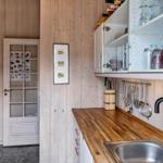 Küche mit Holzwand, Edelstahlspüle und Glasregalen mit Geschirr.