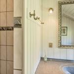 Bad mit Dusche, Waschbecken und Spiegel an weißer Wand.