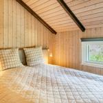 Schlafzimmer mit Bett, Fenster und Holzwandverkleidung.