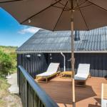 Terrasse mit Liegestühlen und Sonnenschirm neben einem Holzhaus.