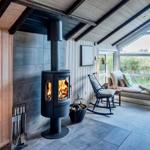 Raum mit Kamin, Sitzgelegenheit und großem Fensterblick auf Grasland.
