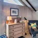 Ein Raum mit Holzwand und Schrank, Sessel und Blick auf Grünflächen.