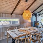 Esszimmer mit Holztisch, Stühlen und Kaminofen. Blick auf Terrasse und Garten.