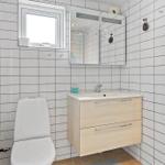 Badezimmer mit Toilette, Waschbecken und Dusche. Wandfliesen und Spiegelschrank.