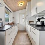 Moderne Küche mit weißen Schränken, dunklem Arbeitsplatz und Holzdecke.