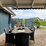 Terrasse mit Tisch und Stühlen unter Dach, Blick auf Garten und Zaun.