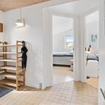 Eingangsbereich mit Holzregal und Blick in Schlafzimmer mit Bett und Fenster.
