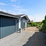 Ein graues Ferienhaus mit gepflastertem Weg und grüner Hecke. Nummer 3 an der Wand.
