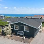 Ein dunkelgrauer Holzhaus mit Blick auf das Meer und einen gepflasterten Hof.