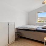 Schlafzimmer mit Bett, Kleiderschrank und Fenster. Holzboden und Stehlampe.